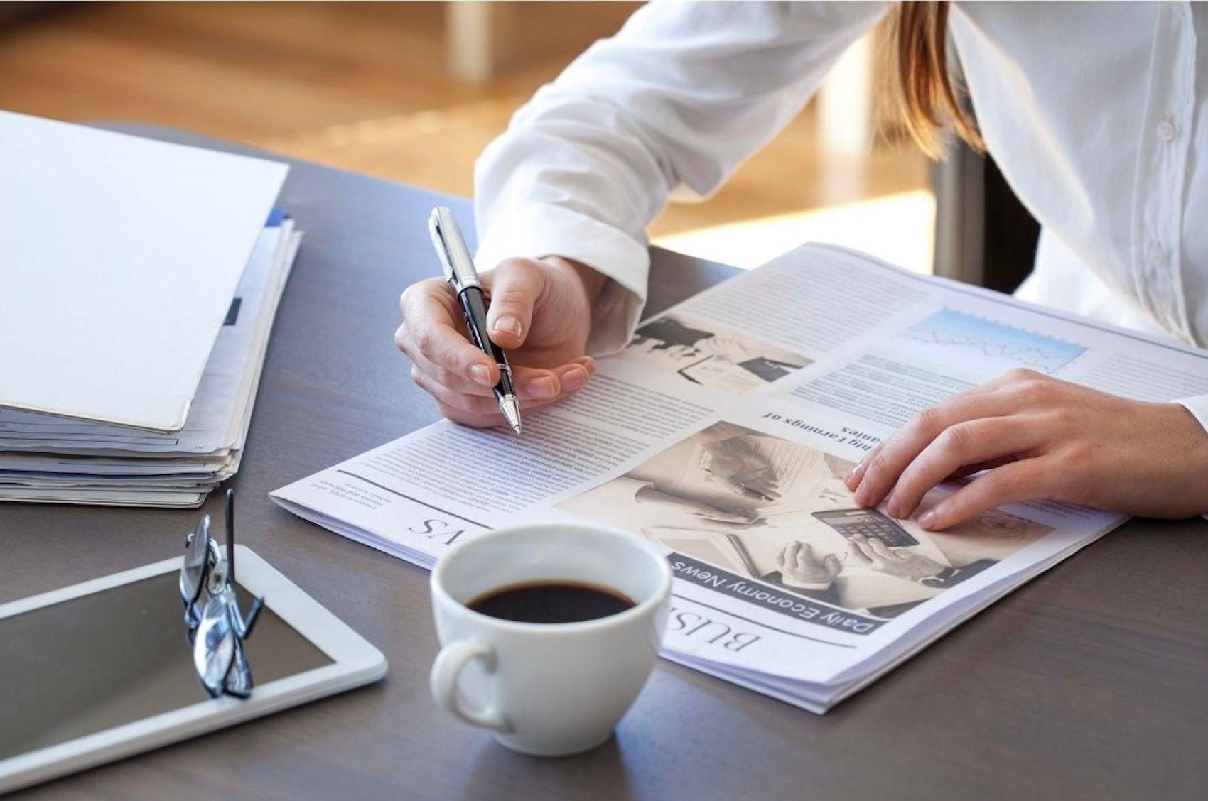 coffee cup and newspaper and pen on table