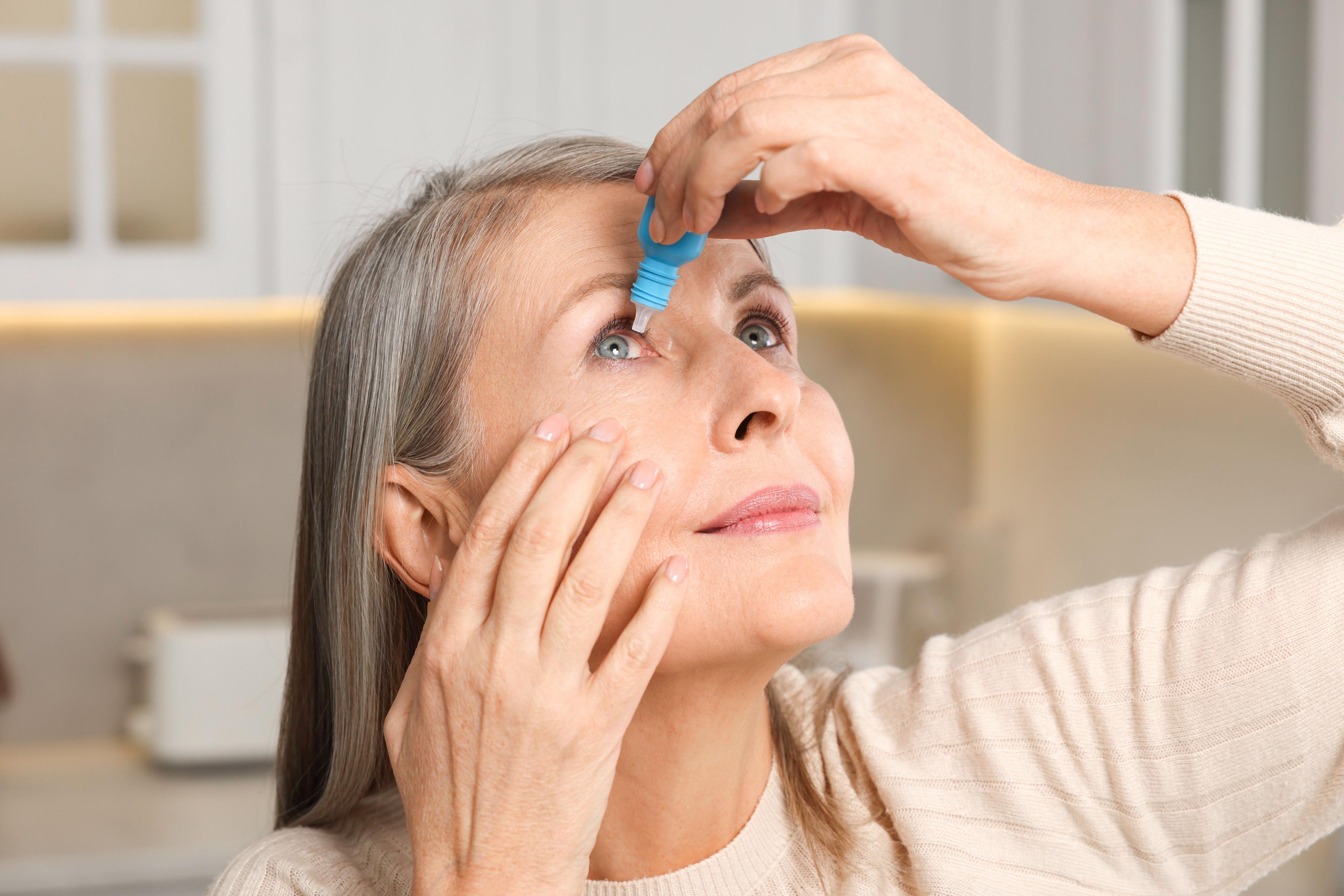 Woman applying eye drops at home / New Africa - stock.adobe.com