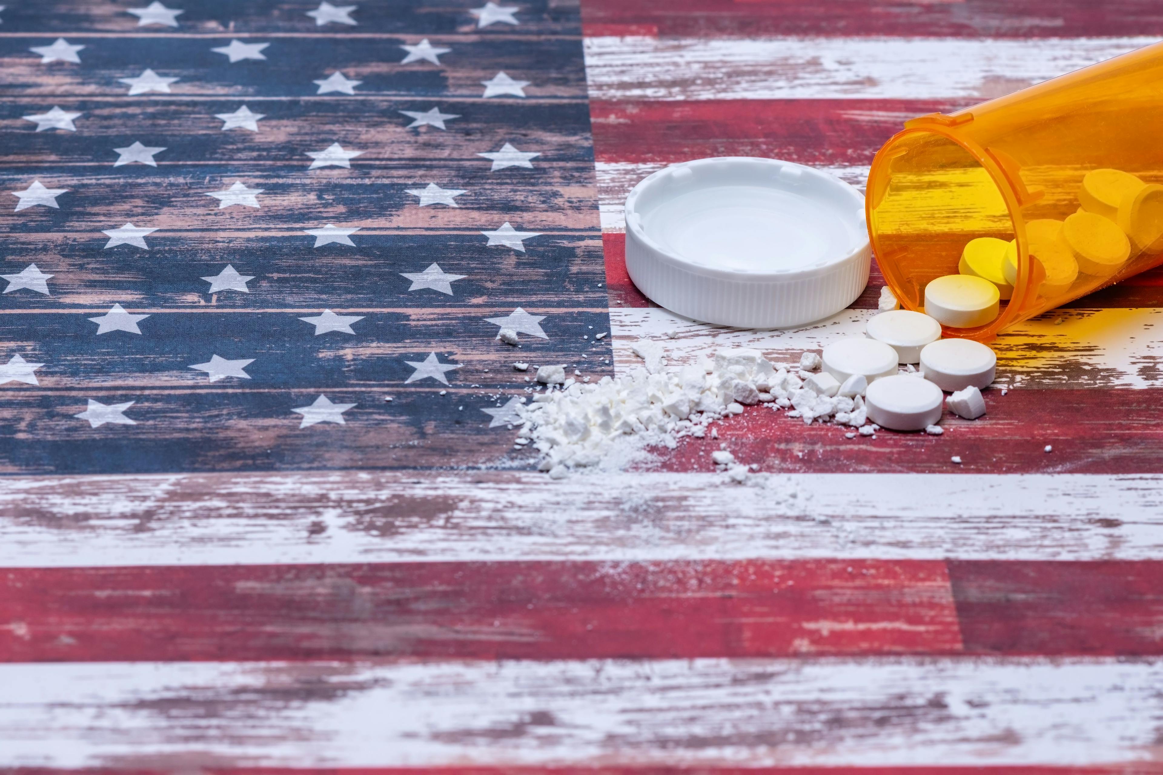 Unidentified pills and powder over American flag / Tim - stock.adobe.com