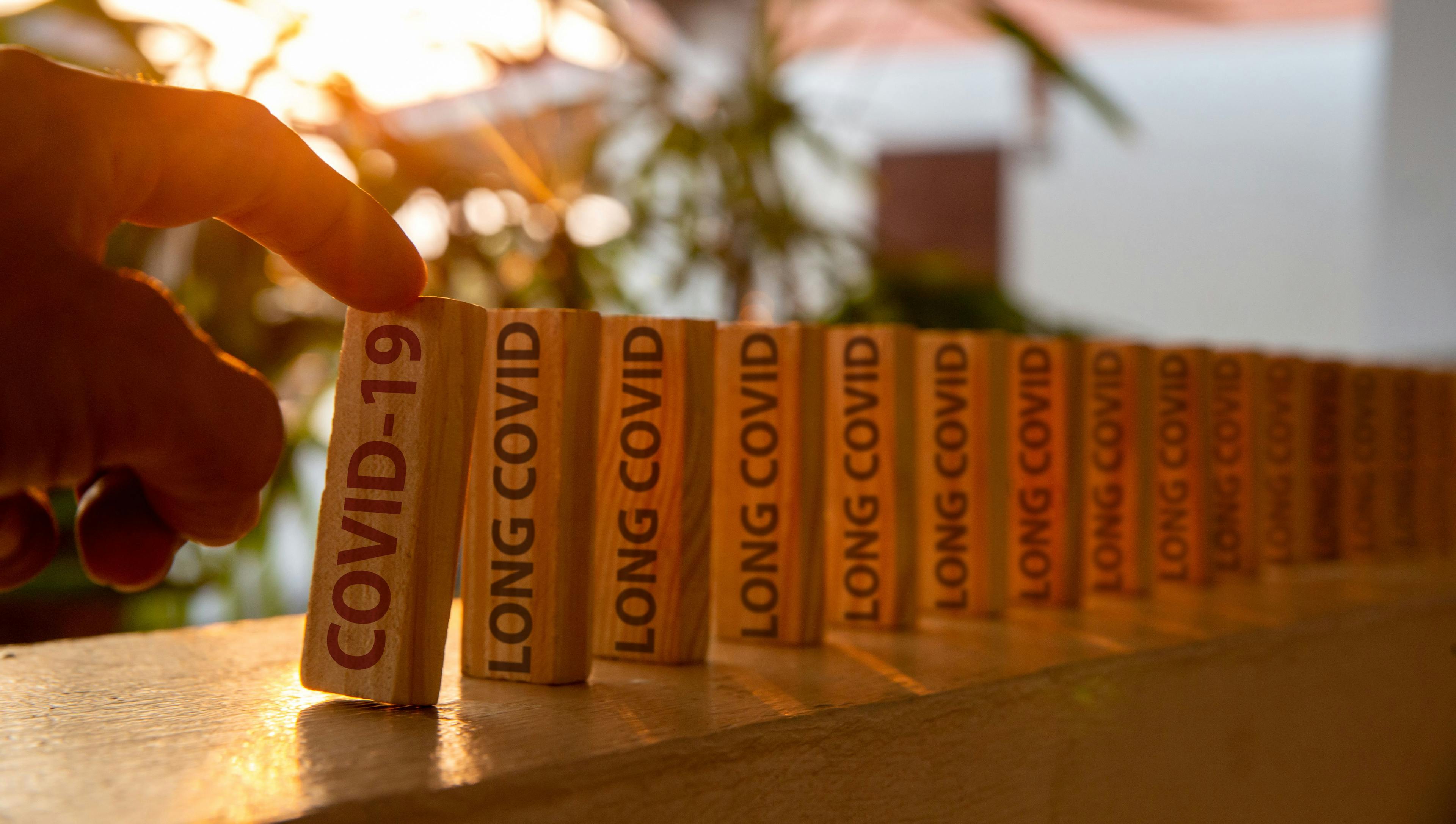 "Long COVID" printed on wooden dominoes / Anucha - stock.adobe.com
